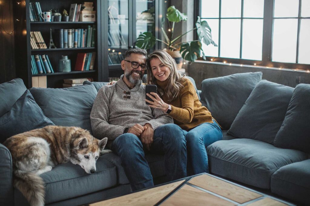 Mature couple at home using video call to talk with friends or family during pandemic isolation period.