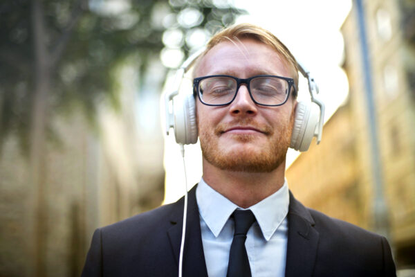 Young while male in business suit wearing headphones