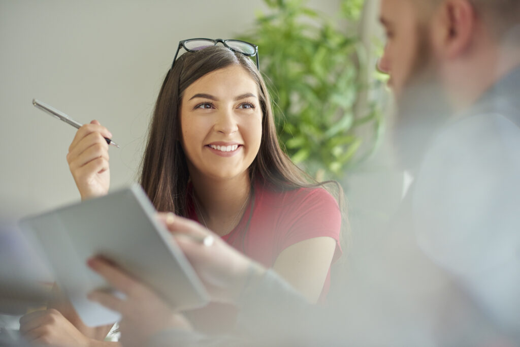 a female university student sits at a desk and chats with her work placement provider .