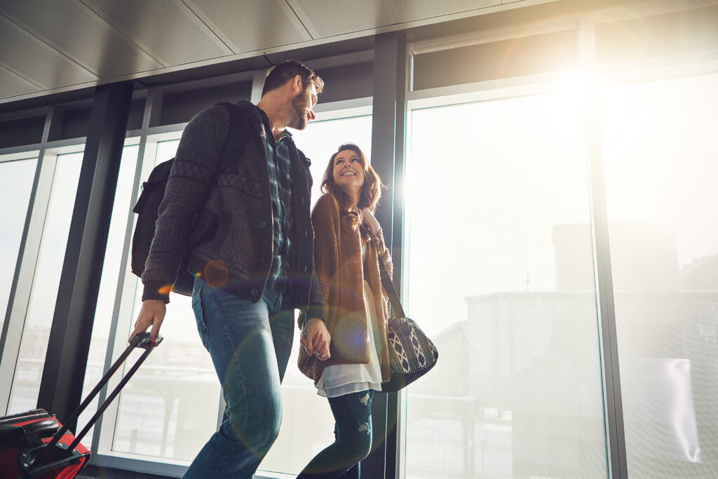 Shot of a young couple walking in anairport with their luggage while holding hands and looking at each other