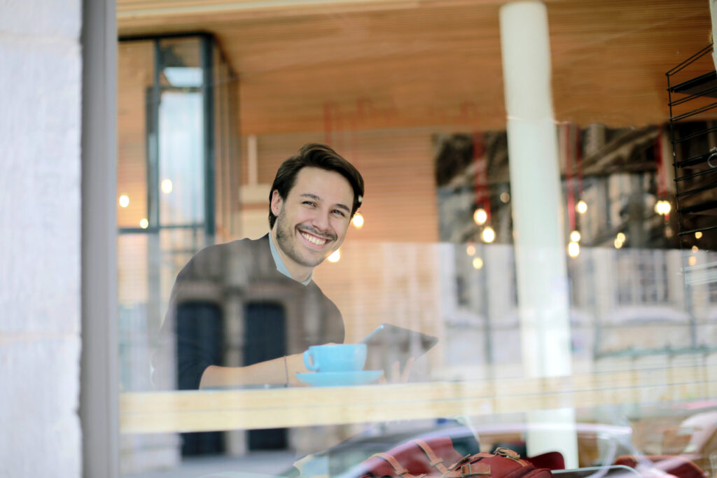 man sitting in coffee shop while browsing on tablet