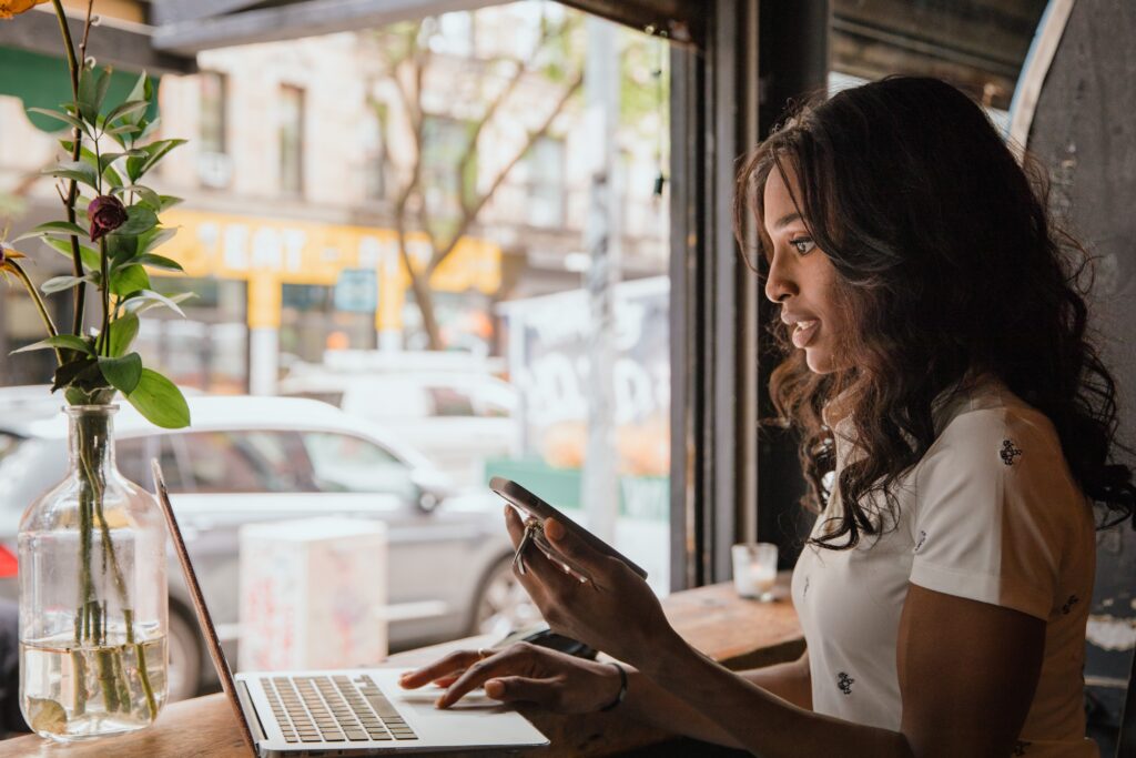 Young adult woman on laptop while sitting in front of large window