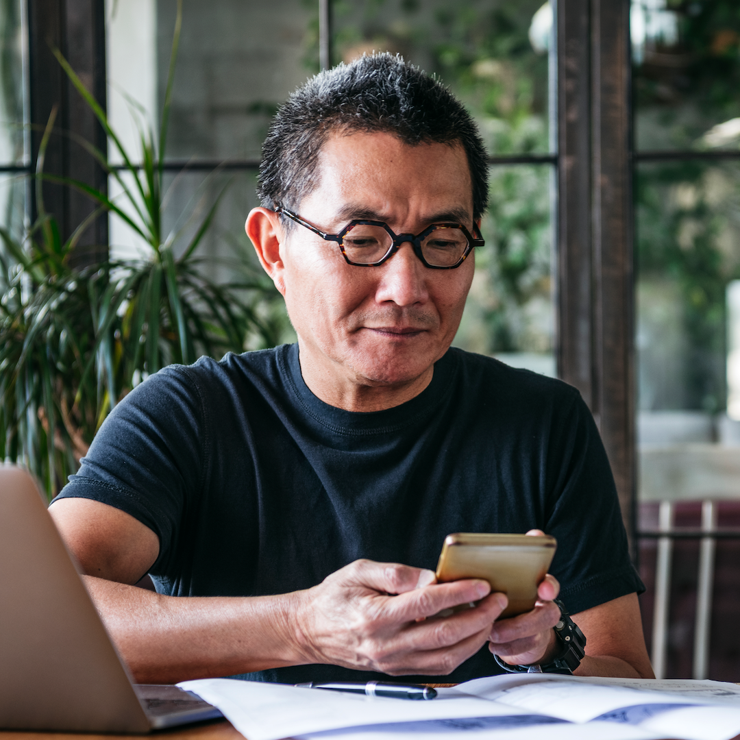 older man looking at his cell phone and doing financial research
