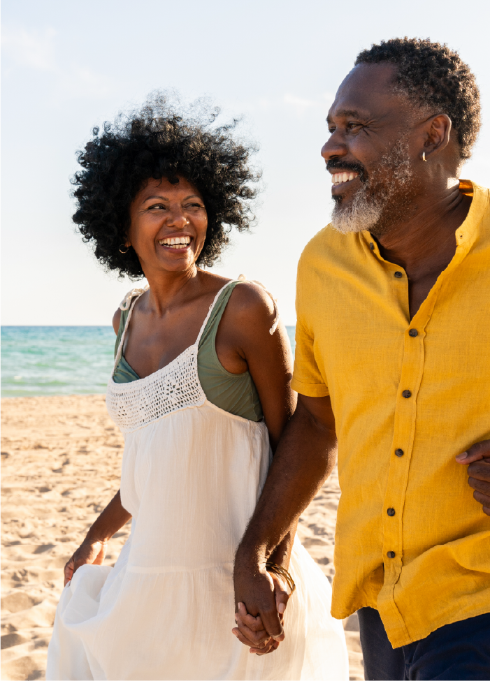 older couple, black man and woman, running happily together on the beach