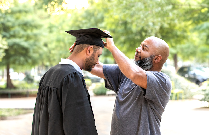 Father adjusting a young man's graduation cap